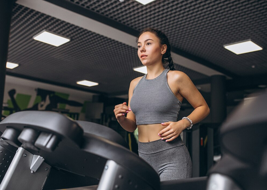 Девушка занимаеться на беговой дорожке